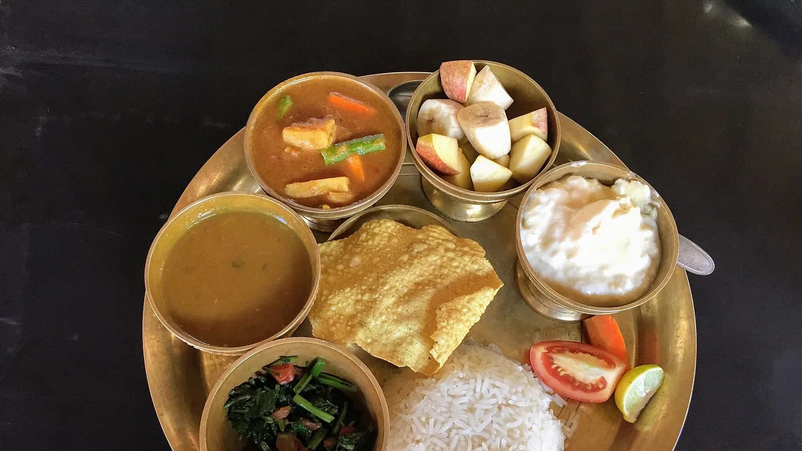 A traditional Nepali dal bhat thali with rice, lentils, curries and pickles