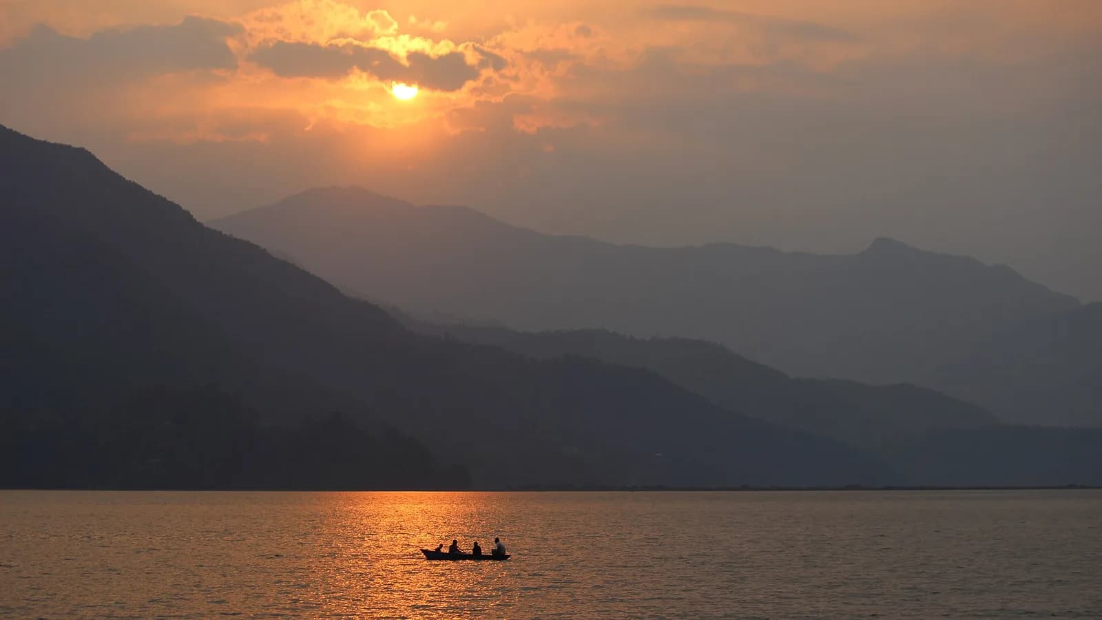 Sunset over Phewa Lake at Pokhara Lakeside, with calm water and hills behind