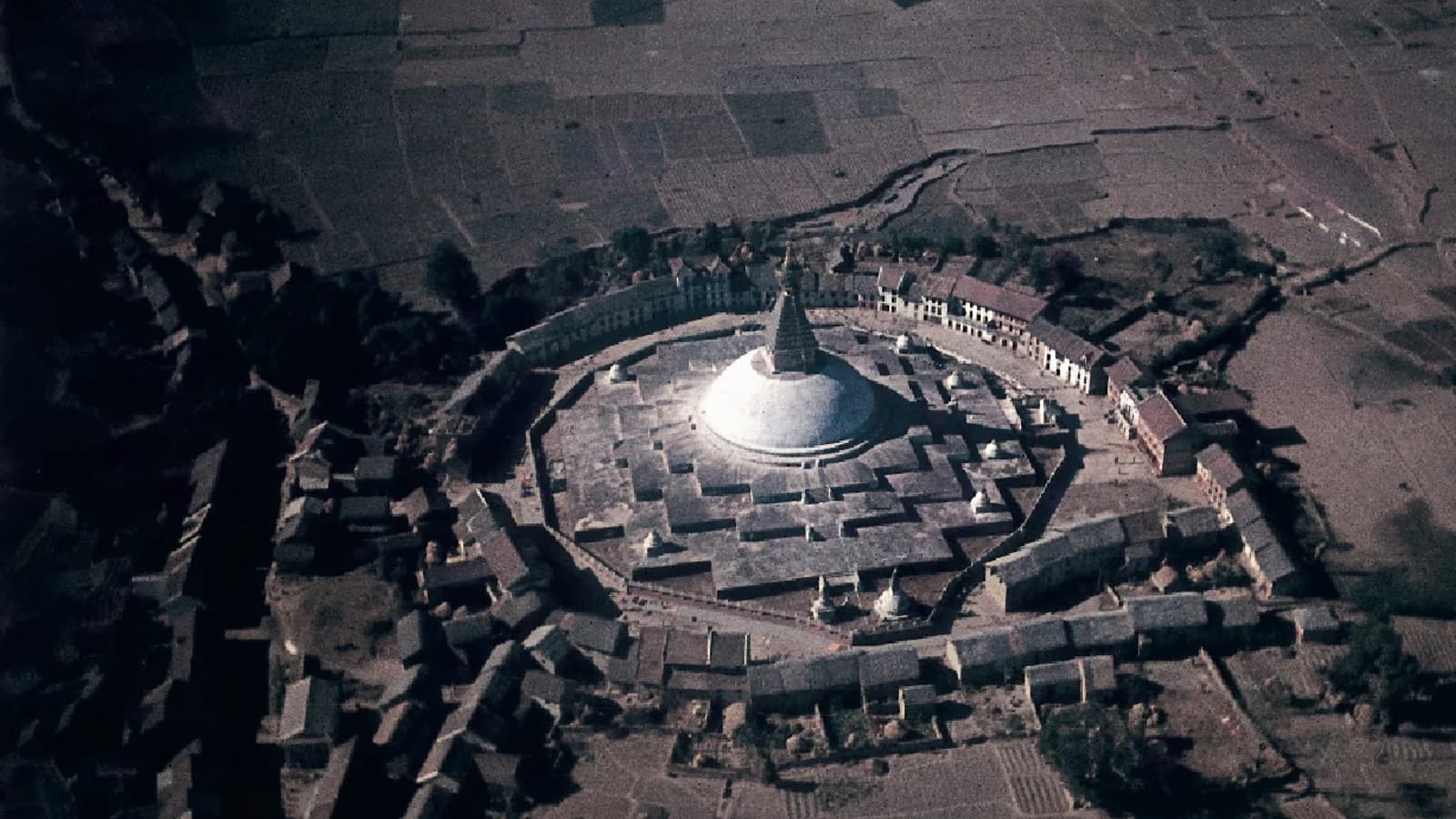 Aerial view of the white dome of Boudhanath Stupa surrounded by the Kathmandu valley