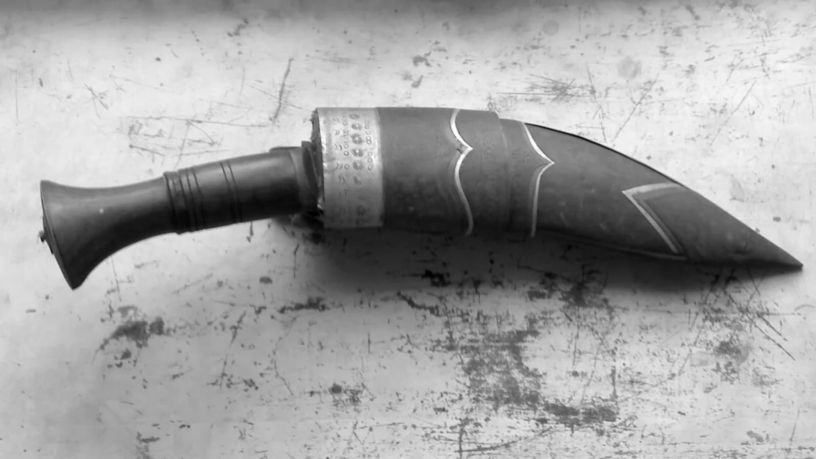 A traditional Nepali khukuri with its forward-curved blade and wooden grip resting in a leather sheath