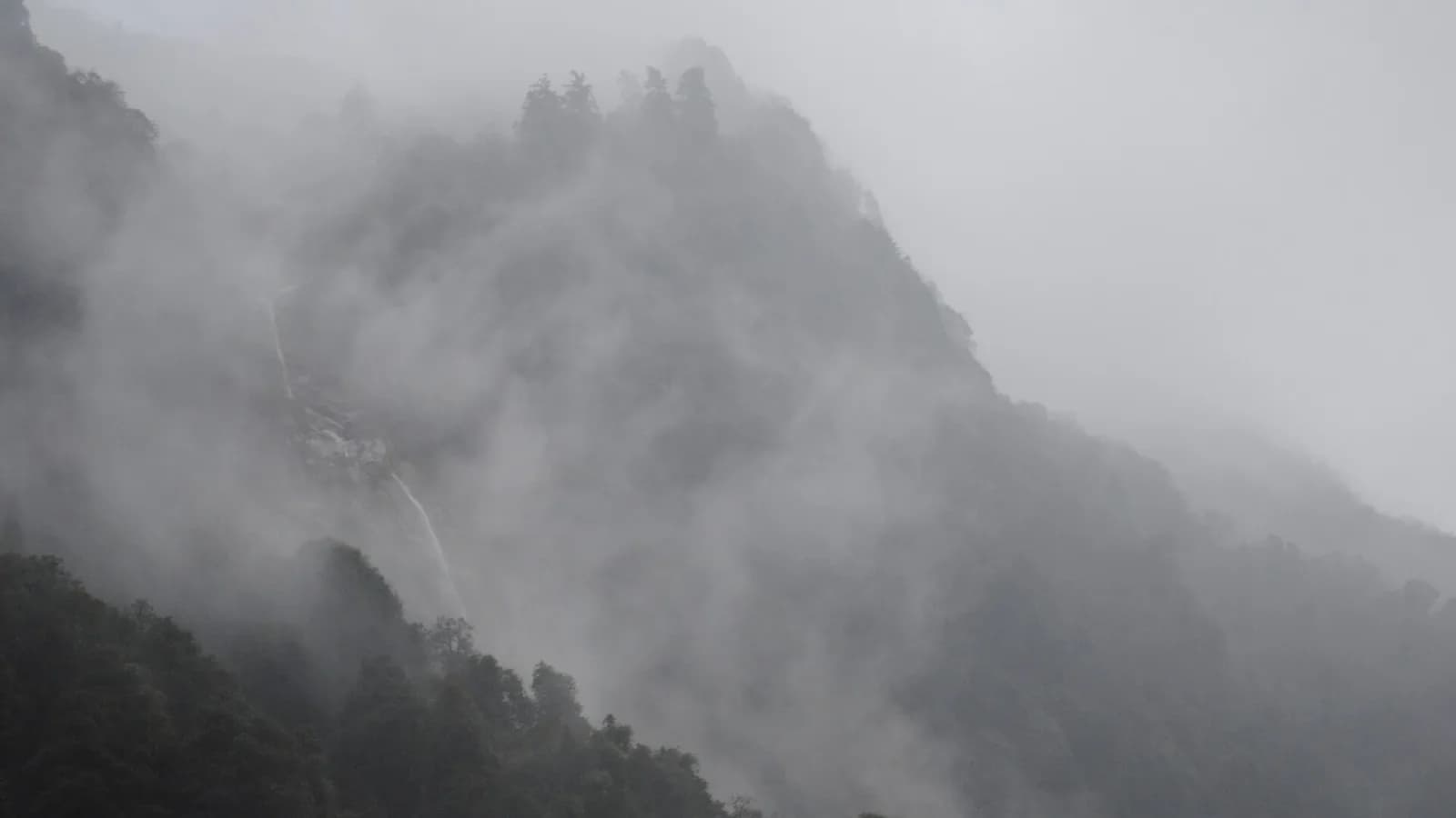 Snow-capped Himalayan peaks rising above a green valley on a trekking route in Nepal.