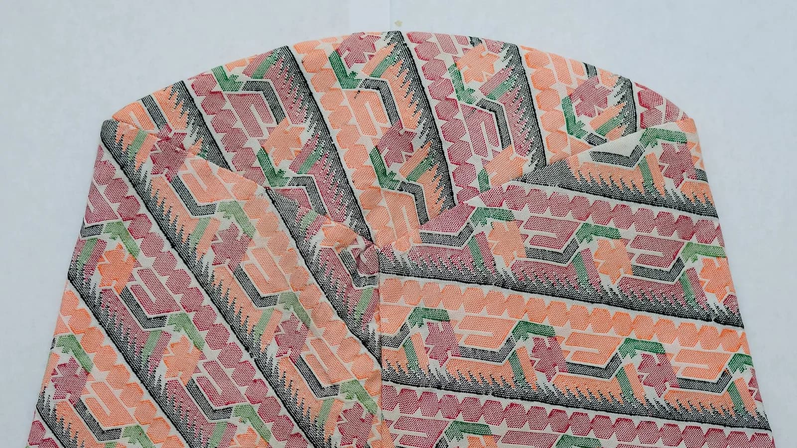 A typical patterned Nepali Dhaka topi cap laid flat on a level surface