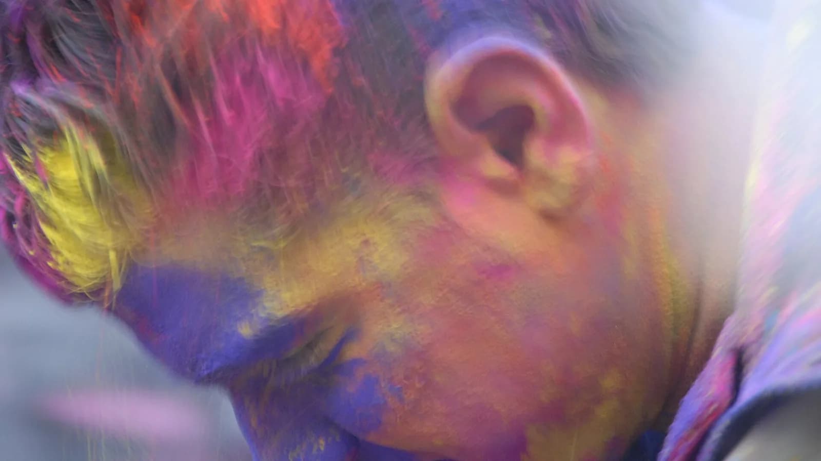 Clouds of bright pink, green and yellow Holi powder filling the air during a festival of colours celebration