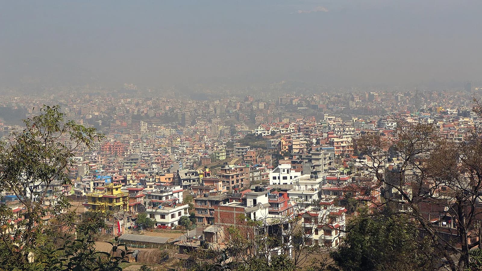 Aerial view across the Kathmandu Valley with the city spread between the surrounding hills