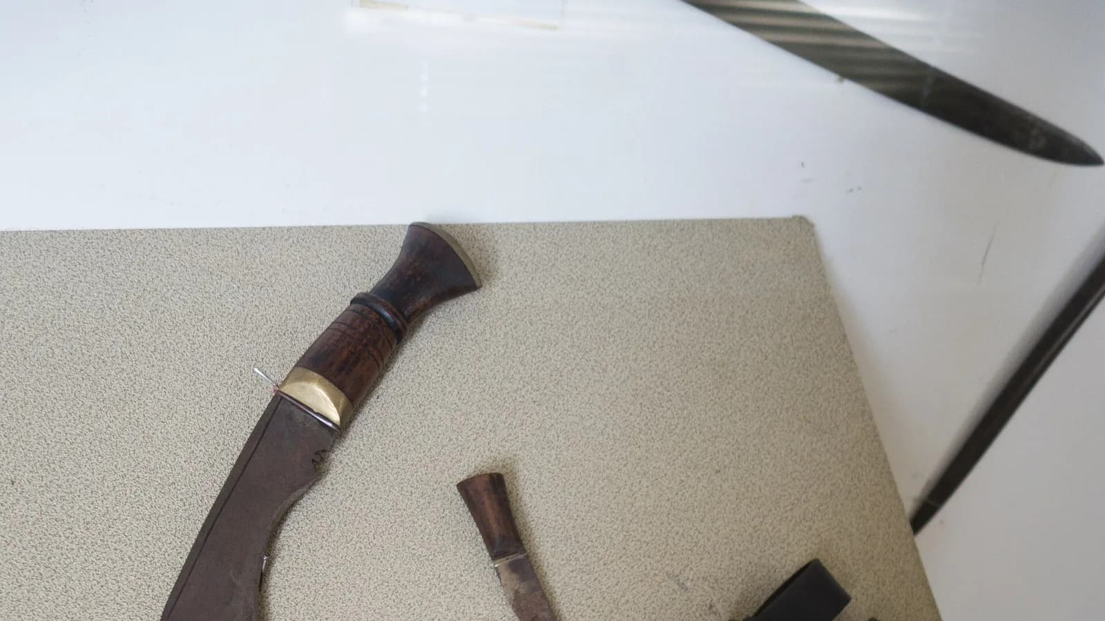 A traditional Nepali khukuri with its forward-curved blade and wooden handle resting in a leather sheath