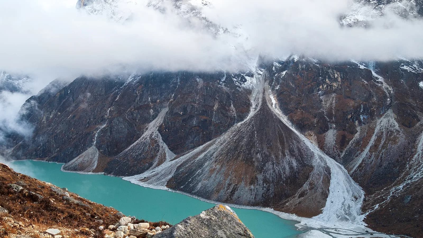 A panorama of the snow-covered Kanchenjunga range on the Nepal–India border, a wall of jagged Himalayan peaks under a clear sky