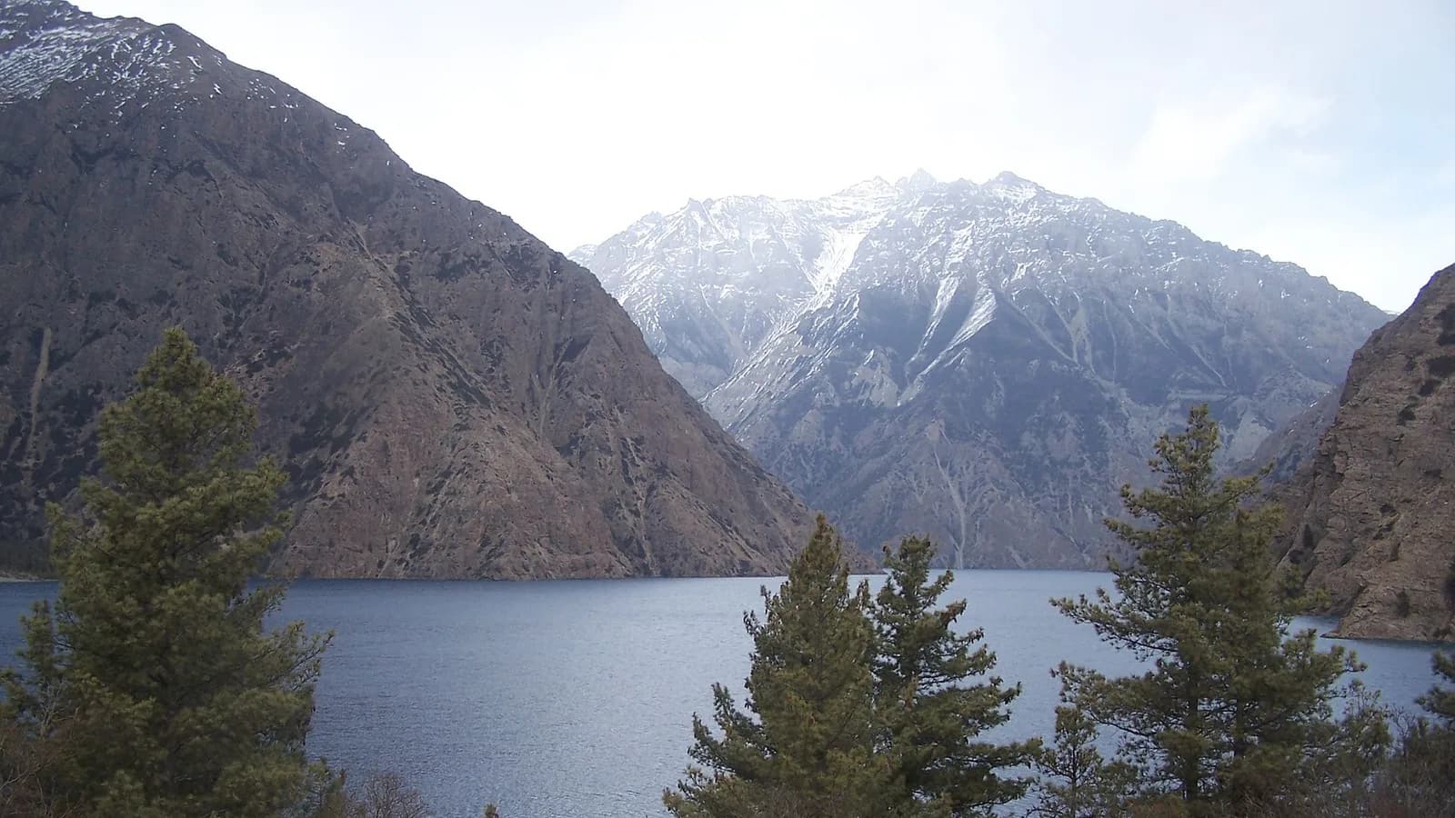 The turquoise water of Phoksundo Lake set against barren cliffs in the remote Dolpo region of western Nepal