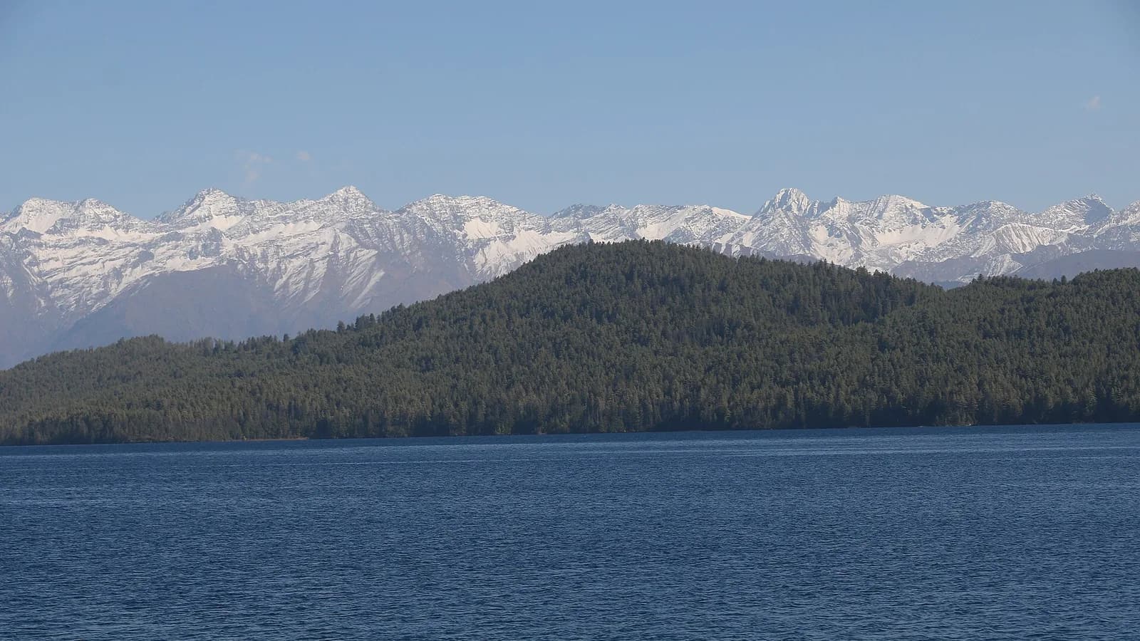The deep blue water of Rara Lake ringed by forested hills in Karnali, Nepal