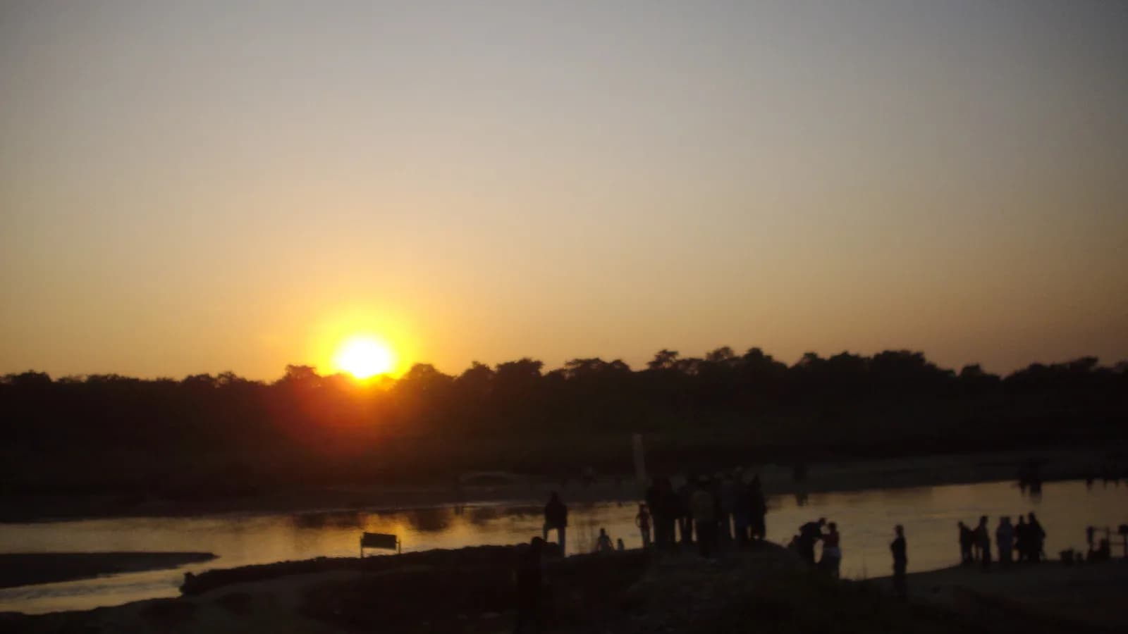 Sunset glowing over the grassland and river haze of Chitwan National Park, the lowland Terai habitat where one-horned rhinos graze and wallow
