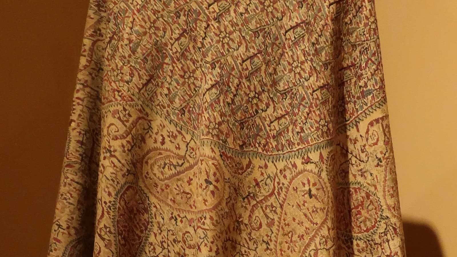 A finely woven antique shawl of the kind sold as pashmina, displayed against a dark background